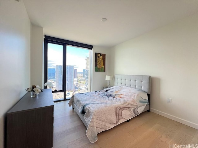 bedroom with access to exterior, light hardwood / wood-style floors, and expansive windows