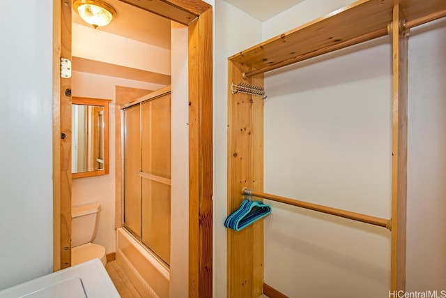 interior space with bath / shower combo with glass door and toilet