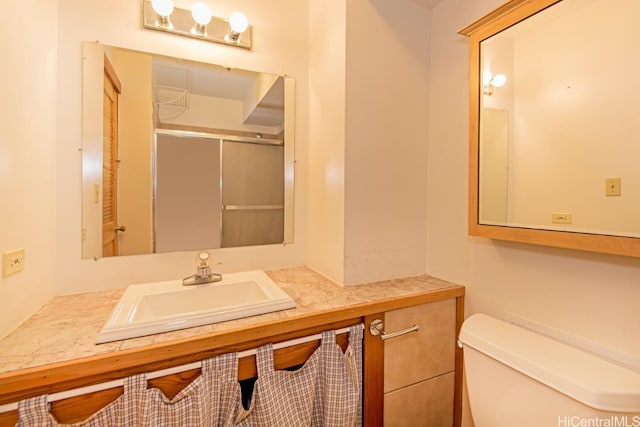 bathroom with vanity, a shower with shower door, and toilet