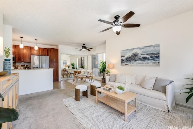 living room featuring ceiling fan, sink, light carpet, and a textured ceiling