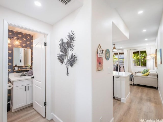 hallway with sink and light hardwood / wood-style floors