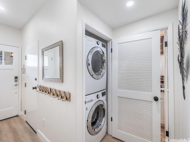 clothes washing area with stacked washer and clothes dryer and light hardwood / wood-style floors