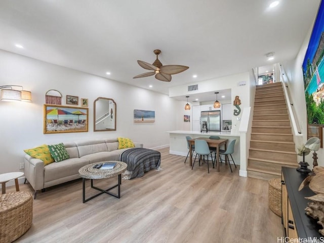 living room featuring light hardwood / wood-style flooring and ceiling fan