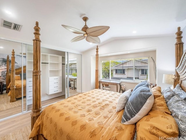 bedroom with multiple closets, vaulted ceiling, ceiling fan, and light hardwood / wood-style flooring