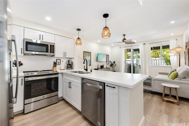 kitchen with stainless steel appliances, sink, white cabinets, and kitchen peninsula