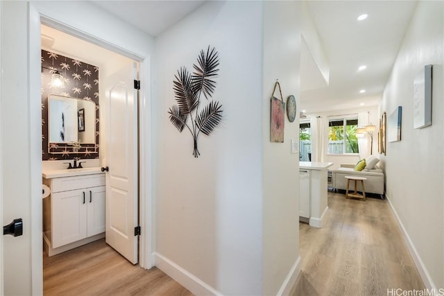 hallway featuring sink and light hardwood / wood-style flooring