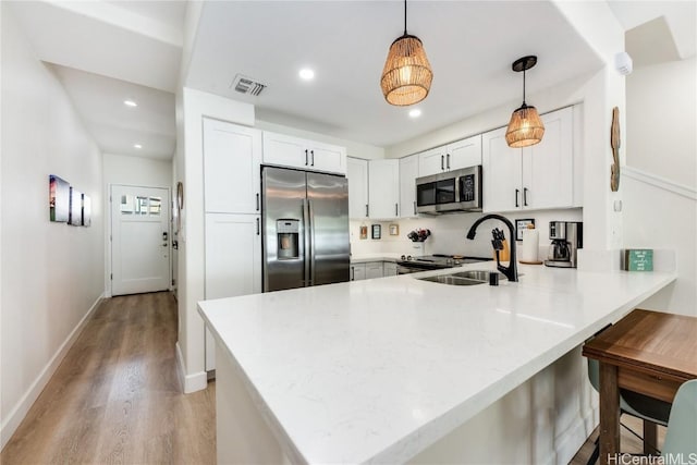 kitchen featuring appliances with stainless steel finishes, decorative light fixtures, sink, white cabinets, and kitchen peninsula