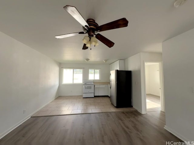 kitchen with white electric range, stainless steel fridge, white cabinets, ceiling fan, and light wood-type flooring