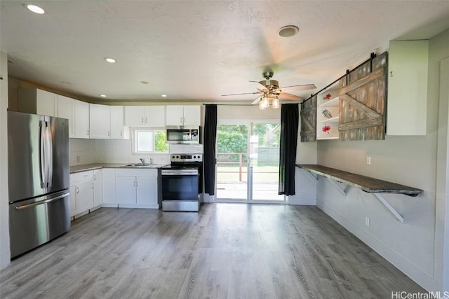 kitchen featuring sink, appliances with stainless steel finishes, white cabinetry, tasteful backsplash, and light hardwood / wood-style floors