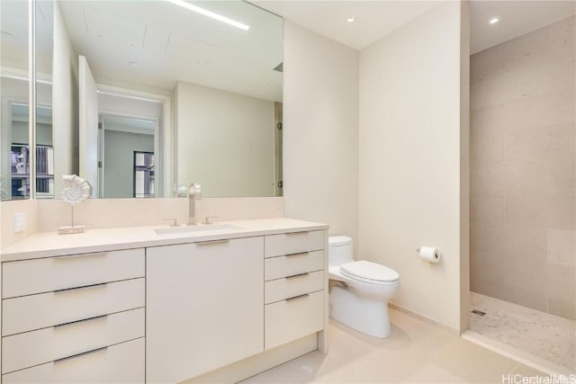 bathroom with vanity, a tile shower, tile patterned floors, and toilet