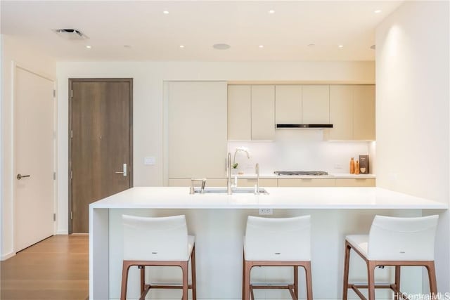 kitchen with white cabinetry, sink, a breakfast bar area, stainless steel gas cooktop, and light hardwood / wood-style floors