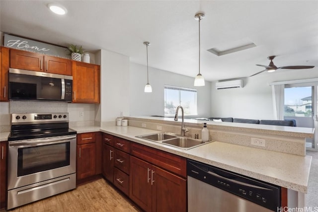 kitchen with appliances with stainless steel finishes, kitchen peninsula, sink, and a wall unit AC