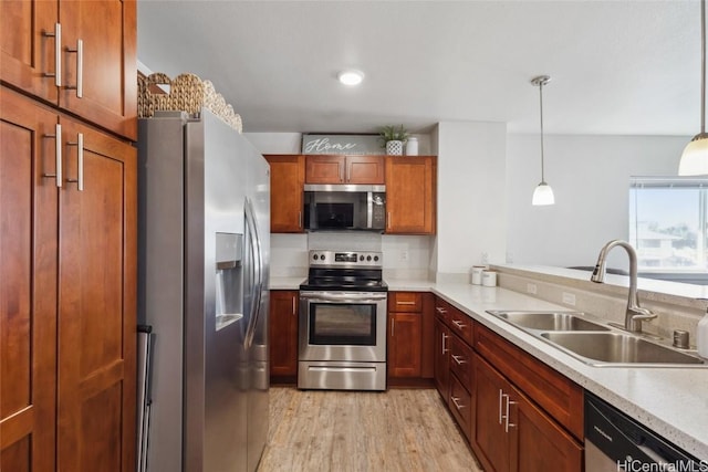 kitchen featuring appliances with stainless steel finishes, light hardwood / wood-style floors, sink, and hanging light fixtures