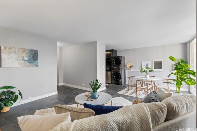 living room featuring stacked washer / drying machine and baseboards