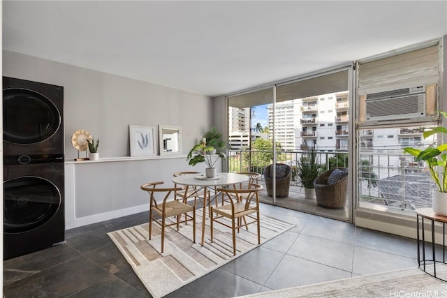 tiled dining space featuring expansive windows, baseboards, a wall unit AC, and stacked washer and dryer