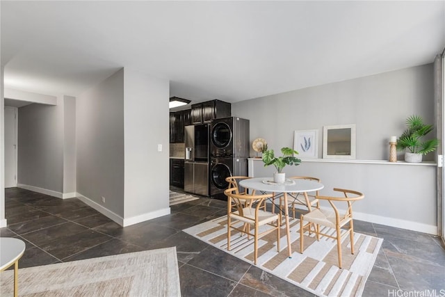 dining space with stacked washer / dryer, baseboards, and stone finish floor