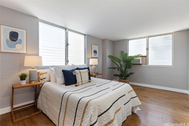 bedroom with baseboards, multiple windows, and wood finished floors