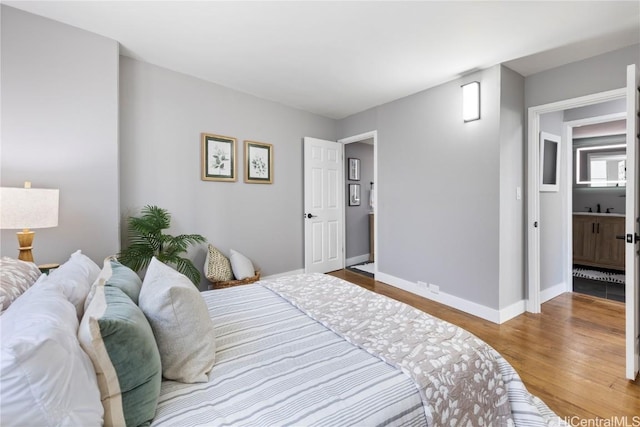 bedroom featuring a sink, baseboards, and wood finished floors