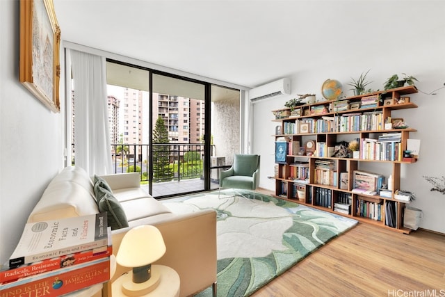 living area with hardwood / wood-style flooring, expansive windows, and a wall mounted air conditioner