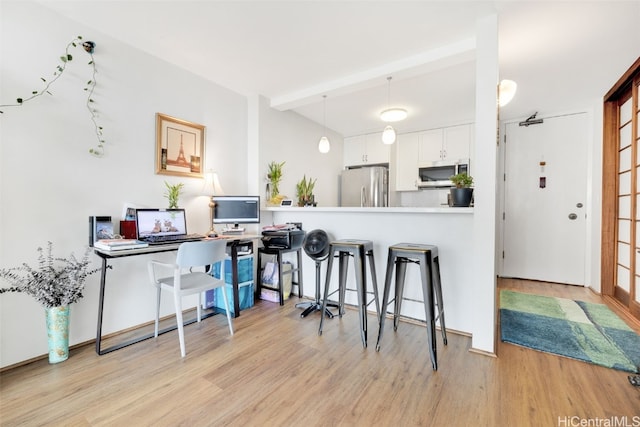 kitchen with appliances with stainless steel finishes, a breakfast bar area, white cabinets, light hardwood / wood-style floors, and kitchen peninsula