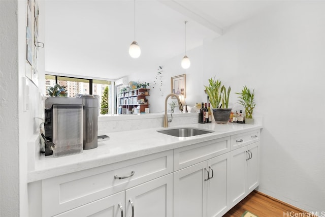 kitchen with sink, light hardwood / wood-style flooring, pendant lighting, light stone countertops, and white cabinets