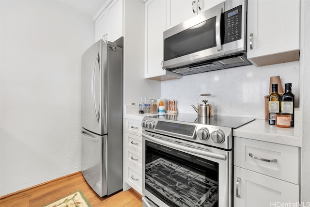 kitchen featuring decorative backsplash, light hardwood / wood-style flooring, white cabinets, and appliances with stainless steel finishes