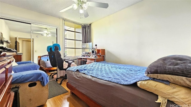 bedroom with a closet, ceiling fan, light hardwood / wood-style floors, and a textured ceiling