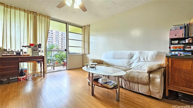 living area featuring ceiling fan, light hardwood / wood-style flooring, and a textured ceiling