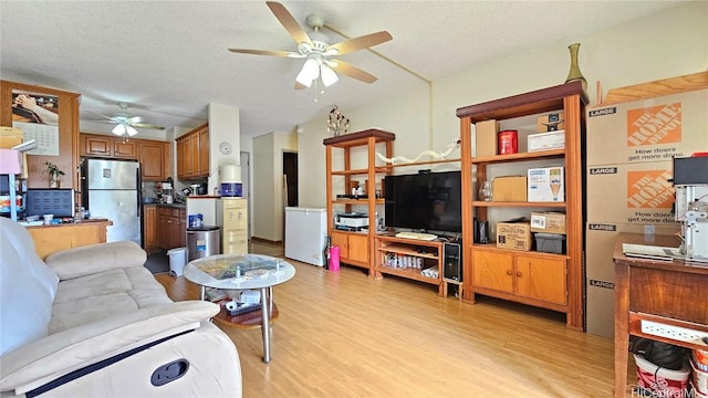 living room featuring ceiling fan, light hardwood / wood-style flooring, and a textured ceiling