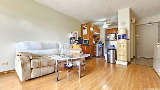 living room featuring ceiling fan, a textured ceiling, and light wood-type flooring