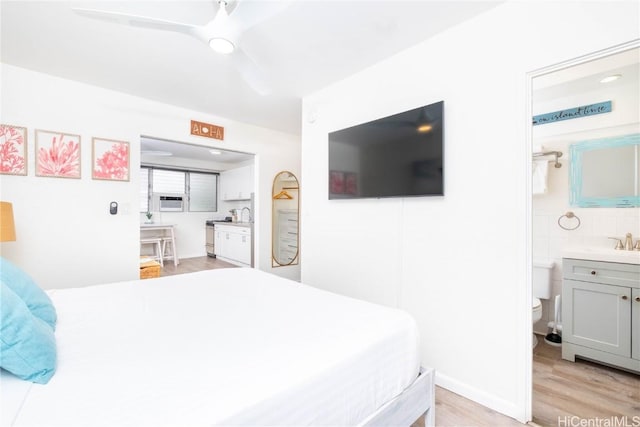 bedroom with ceiling fan, connected bathroom, and light hardwood / wood-style flooring