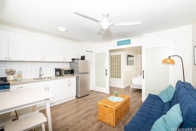 living room with ceiling fan, light hardwood / wood-style floors, and sink