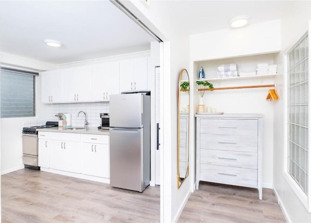 kitchen featuring sink, appliances with stainless steel finishes, tasteful backsplash, light hardwood / wood-style floors, and white cabinets