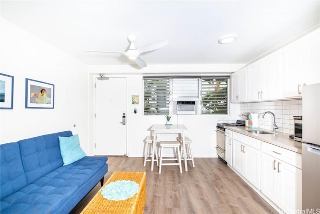 kitchen with white cabinetry, light wood-type flooring, sink, and stainless steel gas stove