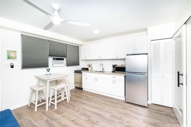 kitchen with sink, white cabinetry, light hardwood / wood-style flooring, stainless steel appliances, and decorative backsplash