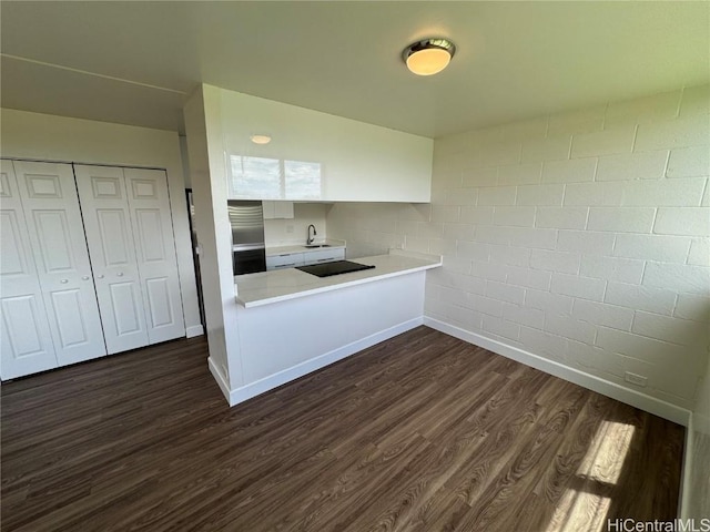 kitchen featuring white cabinetry, sink, stainless steel fridge, dark hardwood / wood-style flooring, and black electric stovetop