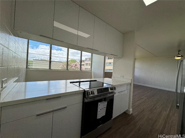 kitchen with dark wood-type flooring, stainless steel range with electric stovetop, a textured ceiling, ceiling fan, and white cabinets