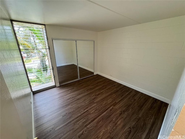 unfurnished bedroom with dark hardwood / wood-style floors and a closet