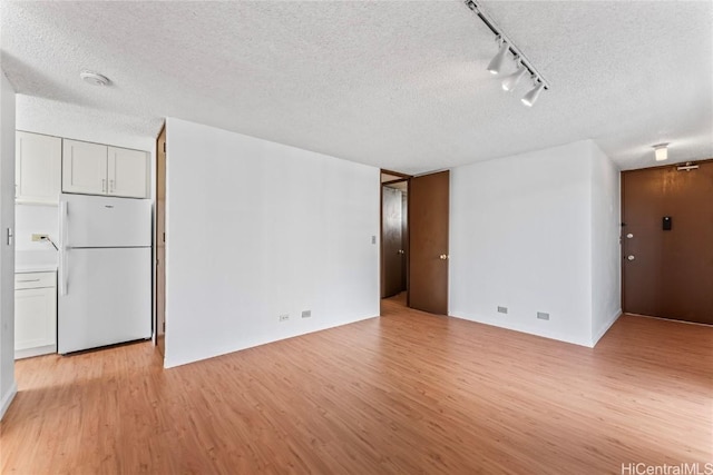 unfurnished room with rail lighting, a textured ceiling, and light wood-type flooring