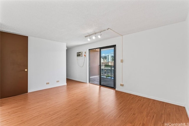 unfurnished room featuring baseboards, a textured ceiling, light wood-style flooring, and track lighting