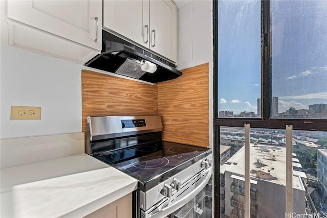 kitchen featuring white cabinetry, light countertops, stainless steel range with electric stovetop, and under cabinet range hood