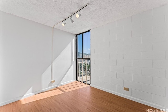 spare room featuring a wall of windows, baseboards, a textured ceiling, and wood finished floors