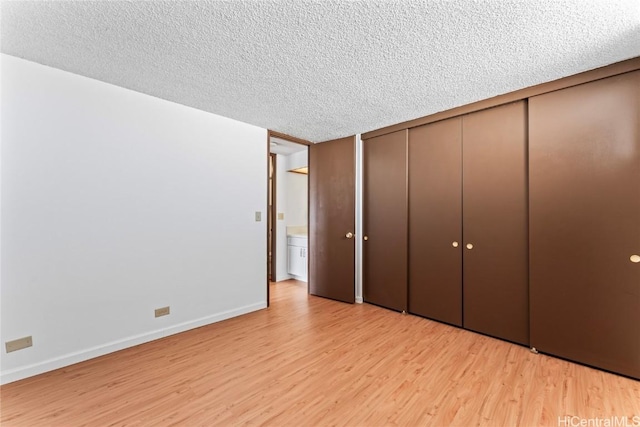 unfurnished bedroom featuring a closet, baseboards, light wood-style floors, and a textured ceiling