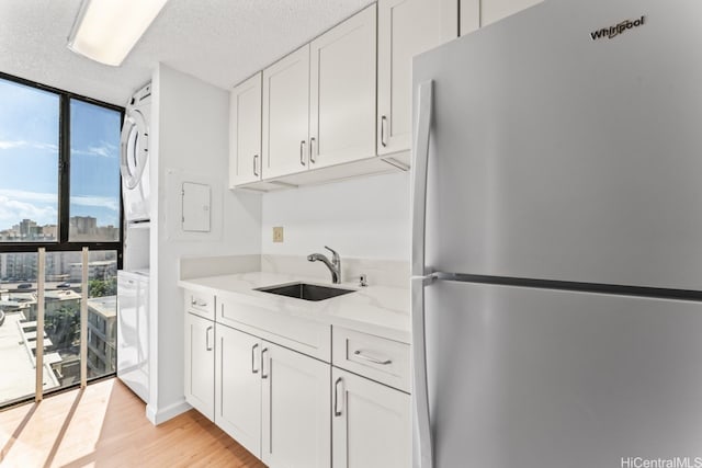 1415 Liholiho St Unit 909, Honolulu, HI 96822 - kitchen with freestanding refrigerator, a wall of windows, a sink, white cabinetry, and stacked washing machine and dryer