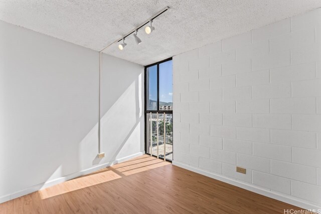 1415 Liholiho St Unit 909, Honolulu, HI 96822 - empty room with a wall of windows, wood finished floors, track lighting, a textured ceiling, and baseboards