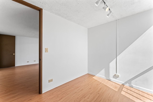 1415 Liholiho St Unit 909, Honolulu, HI 96822 - spare room featuring rail lighting, a textured ceiling, wood finished floors, and baseboards