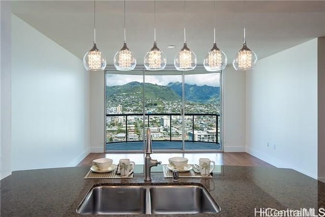 kitchen featuring a mountain view, sink, hanging light fixtures, and dark stone countertops