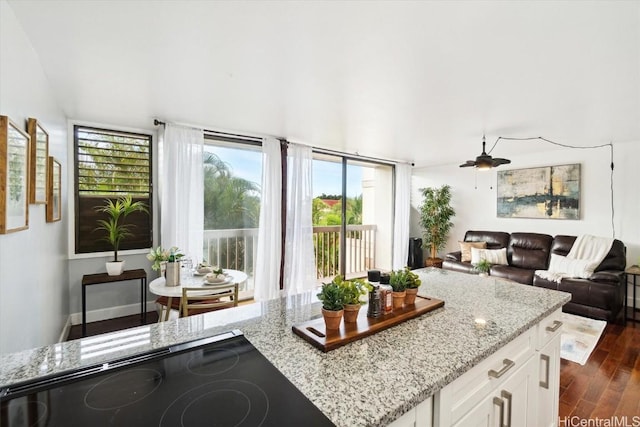 kitchen with ceiling fan, white cabinetry, dark hardwood / wood-style floors, black stovetop, and light stone countertops