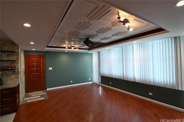 empty room with hardwood / wood-style floors, a tray ceiling, and ceiling fan