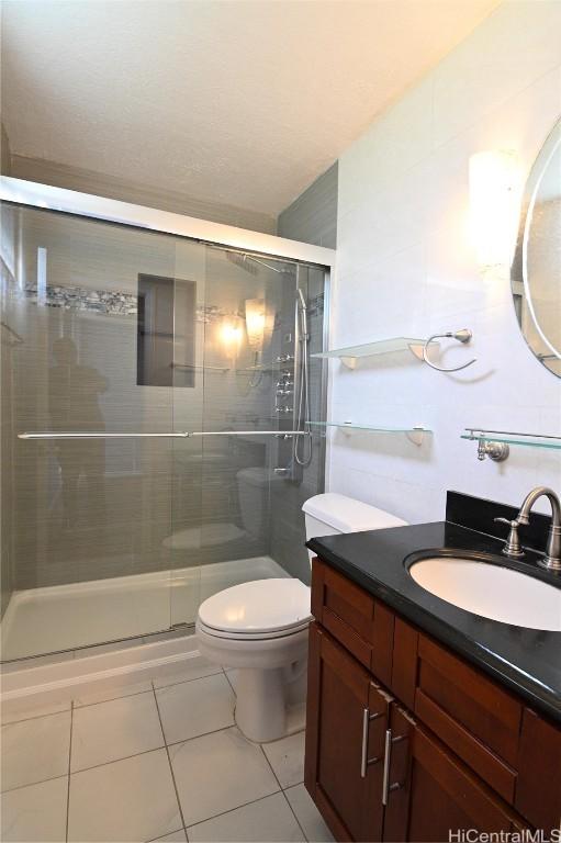 bathroom with vanity, tile patterned flooring, a shower with shower door, and toilet